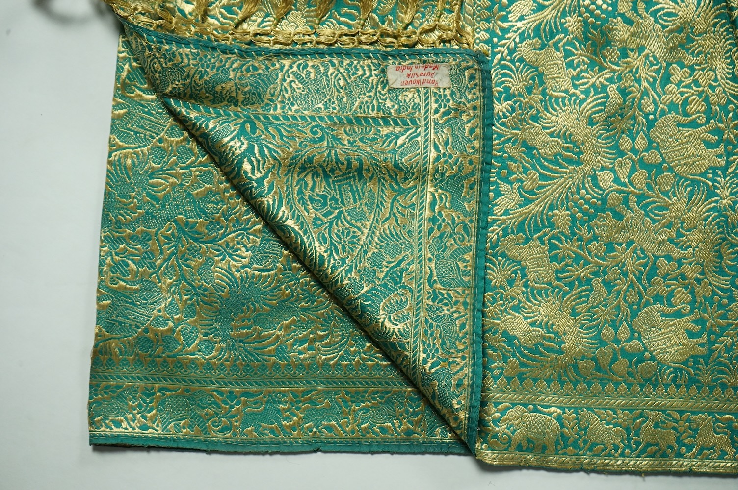 An Indian green and gold silk hand woven brocade stole, a cream pashmina embroidered stole and a similar finely woven and embroidered lilac stole (3). Brocade stole 38cm x 180cm., Condition - light stain to finely woven